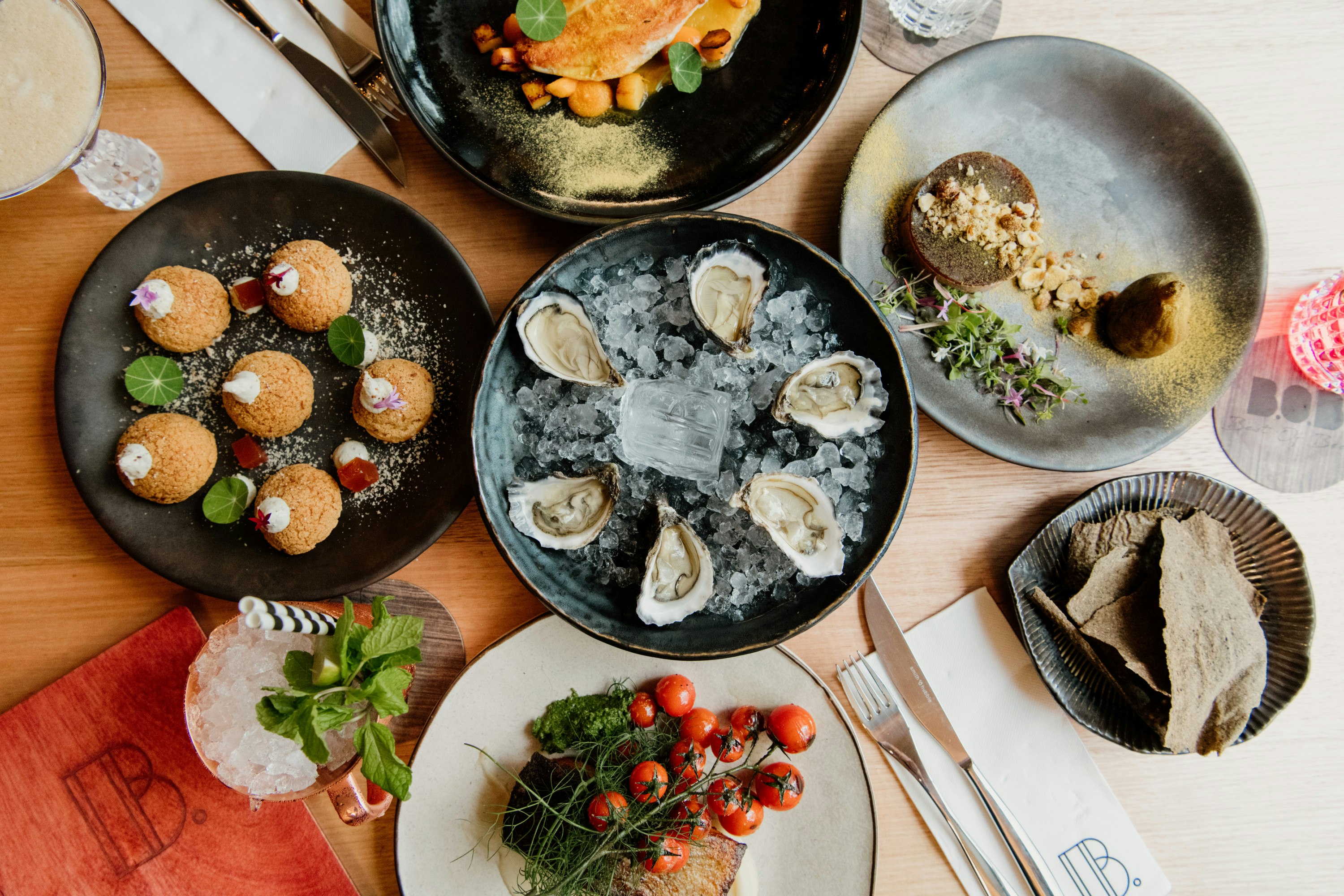 a table atop which sit several dishes including oysters, profiteroles and other